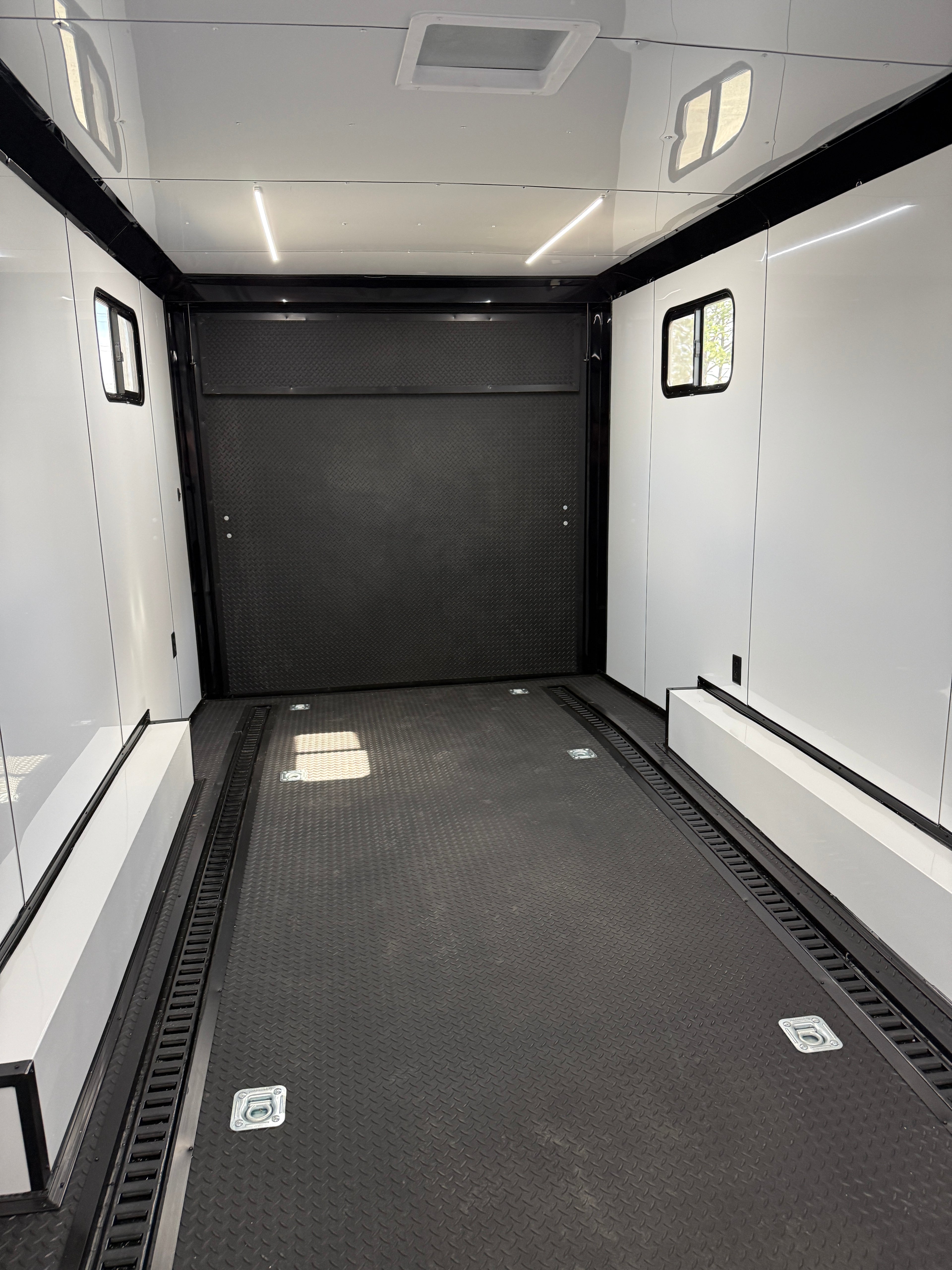 Modern elevator interior with black doors and white walls.